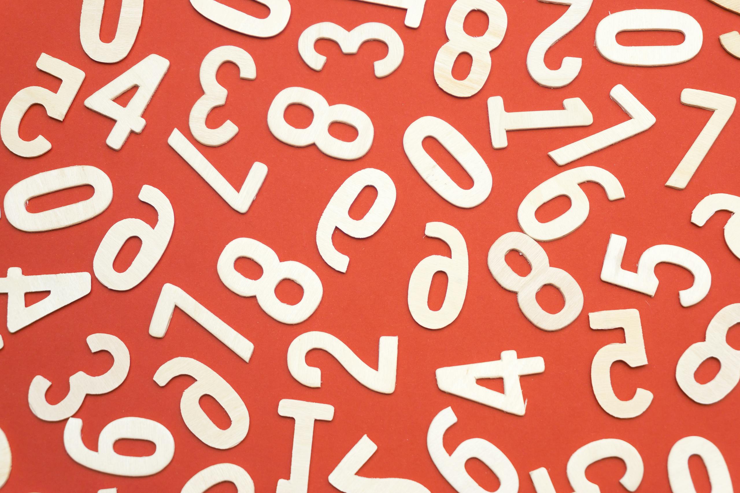 Artistic scattered white numbers on a bright red background, geometric and abstract.